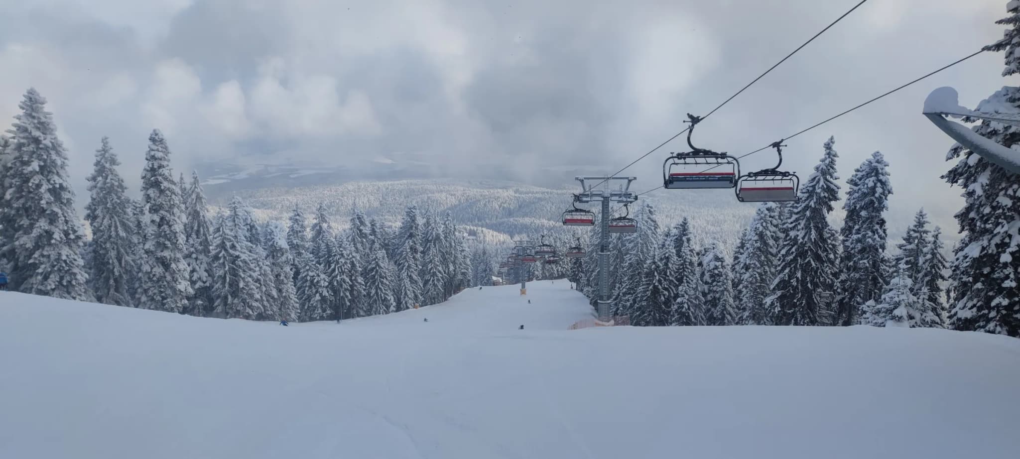 Chairlift line on Martinovi Baraki, Borovets, with fog rolling over the valley below.
