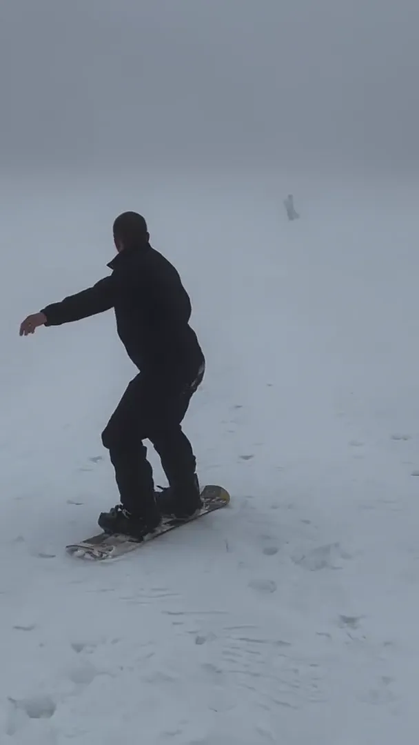 Snowboarder learning the fundamentals riding an empty slope in dense fog