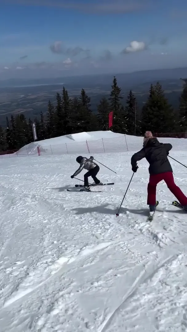 Two skiers turning on an open ridge with the Rila valley far below them