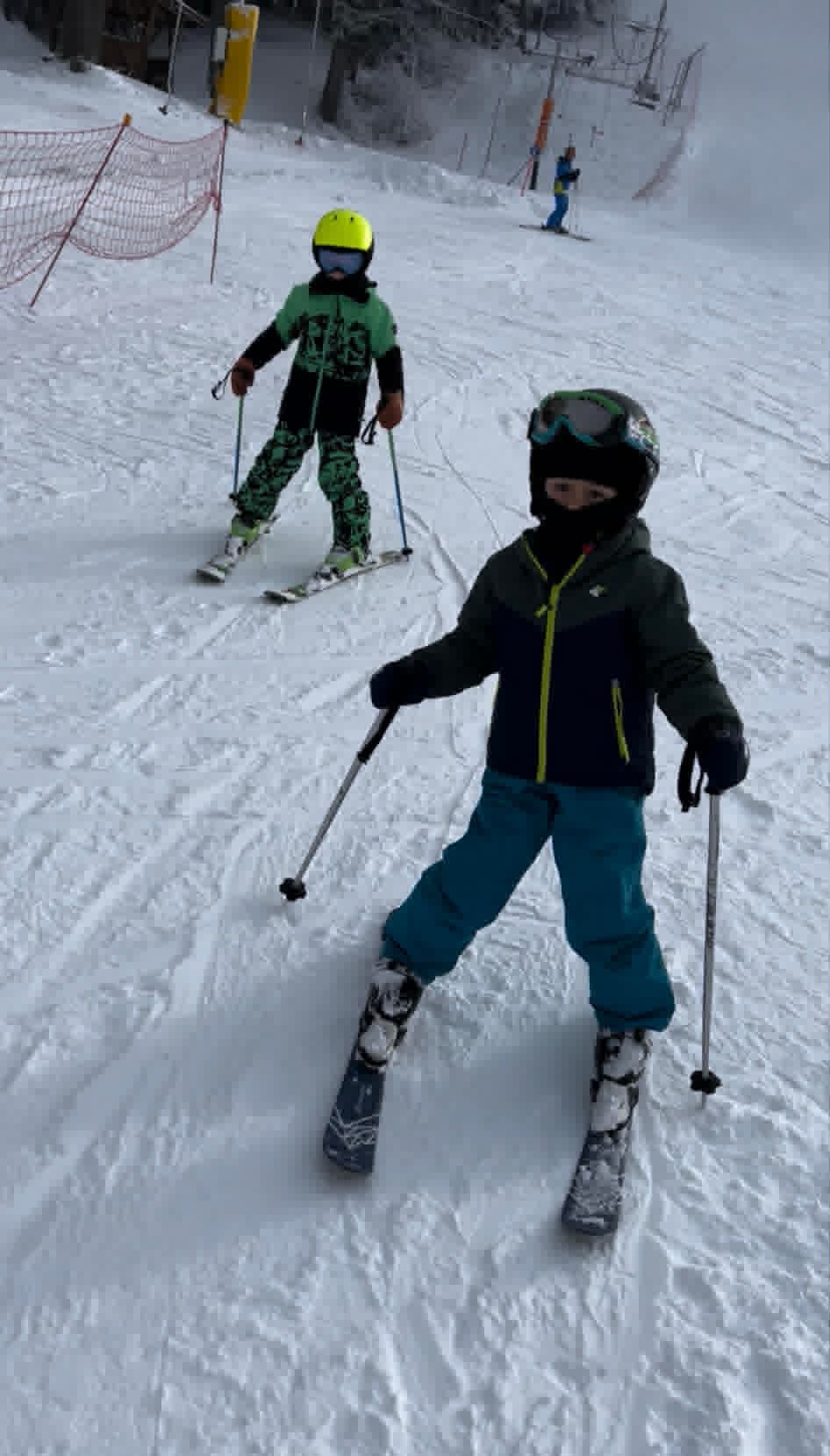 Children following the ski instructor down a green slope