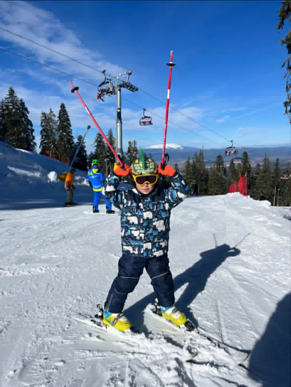 Small child ready to ski under the chairlift slope