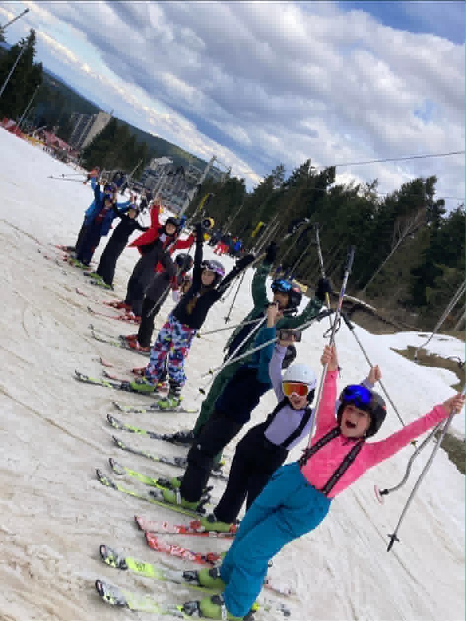 Instructor and a group of students warming up on a green slope