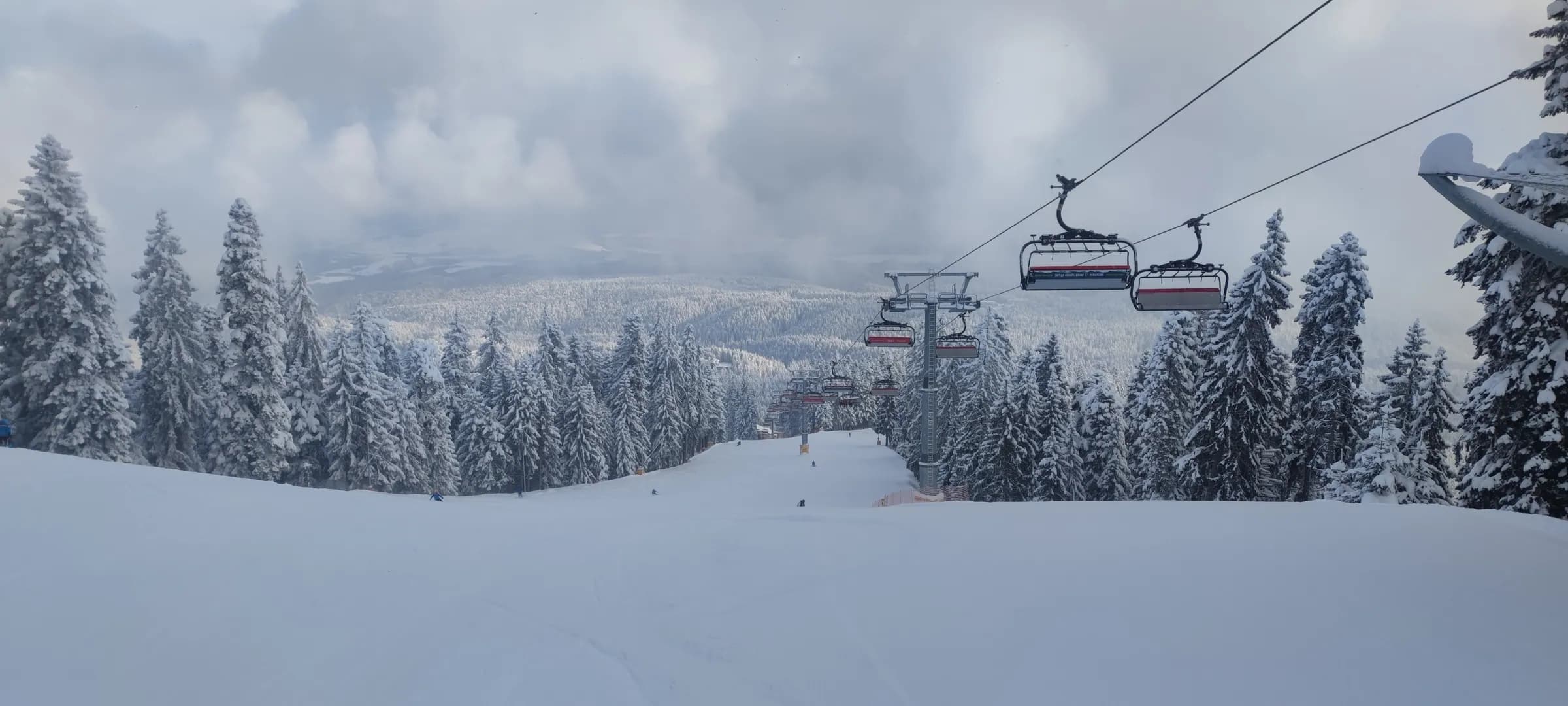 Chairlift line on Martinovi Baraki, Borovets, with fog rolling over the valley below.